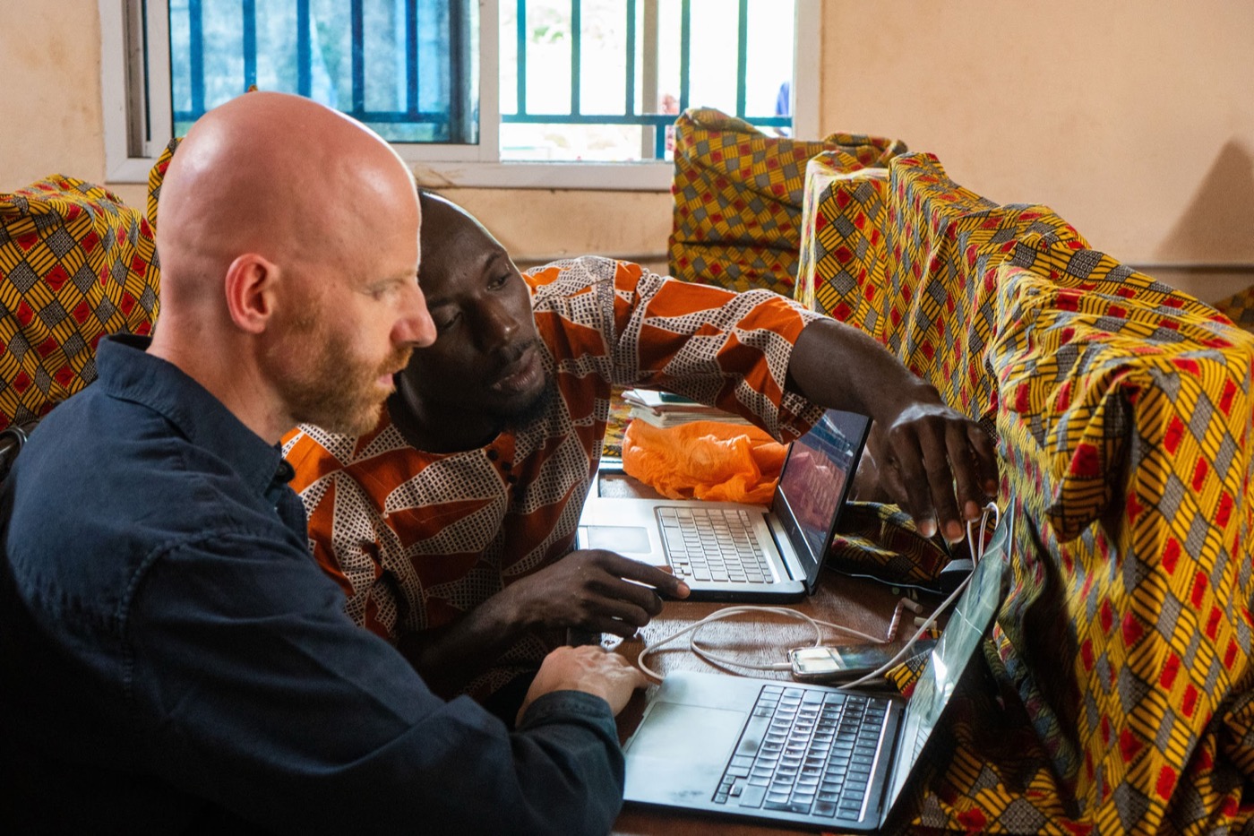 Shane and a colleague working together on laptops in The Gambia
